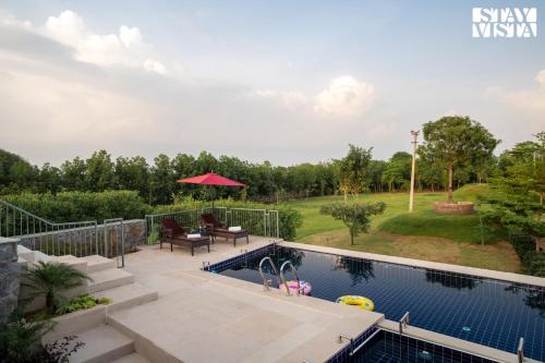 a swimming pool in a backyard with a table and chairs at StayVista at The Stone Age Home with Pool, Lawn, BBQ & Bonfire in Jaipur