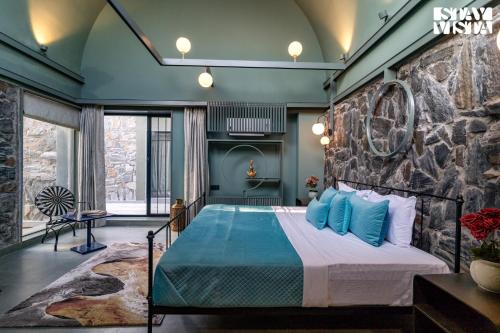 a bedroom with a large bed with blue pillows at StayVista at The Stone Age Home with Pool, Lawn, BBQ & Bonfire in Jaipur