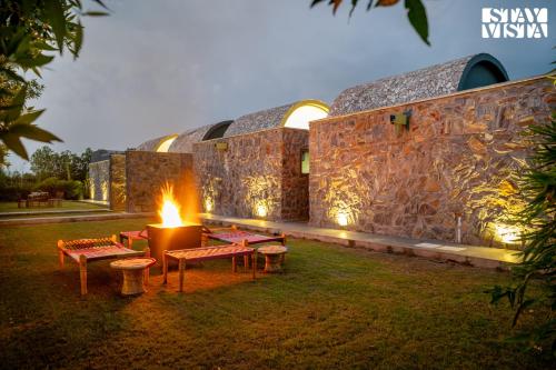 a building with benches and a fire in the yard at StayVista at The Stone Age Home with Pool, Lawn, BBQ & Bonfire in Jaipur