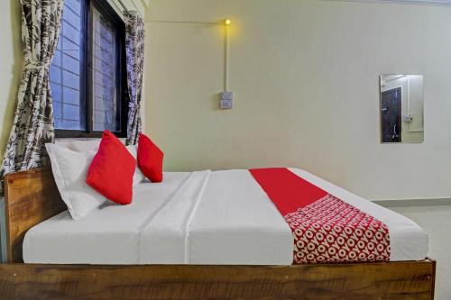 a bedroom with a bed with red pillows on it at Hotel O Sai Executive Lodging in Māngvādi