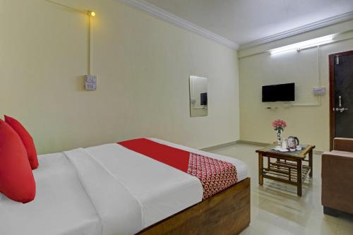 a bedroom with a bed and a table and a television at Hotel O Sai Executive Lodging in Māngvādi