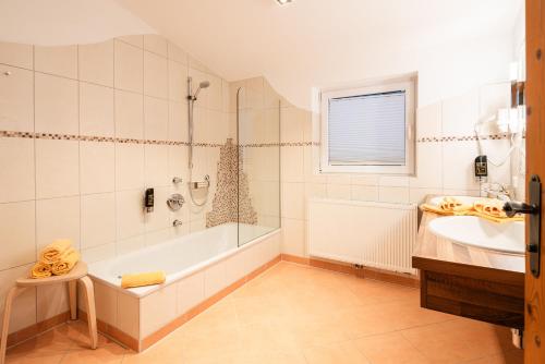 a bathroom with a tub and a sink at Apparthotel AlpenChalet in Neukirchen am Großvenediger