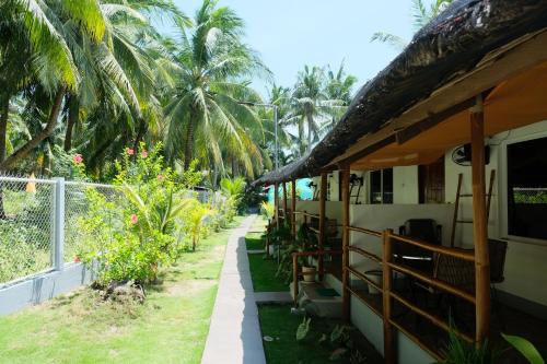 a house with a pathway next to a fence at Skott's Comfy Lodge in Bantayan Island