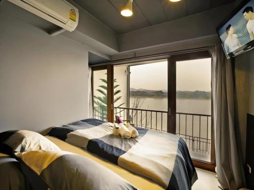 two beds in a room with a large window at Chic Chiangkhan Hotel in Chiang Khan