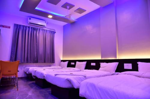 three beds in a room with purple lighting at Hotel President Palace, Akkalkot in Akalkot