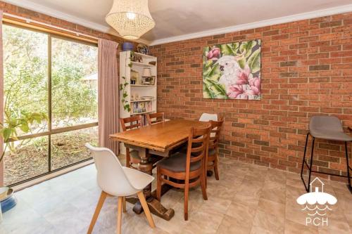 comedor con pared de ladrillo y mesa y sillas de madera en Wattle Haven Stay 3 Pay 2 Sept to Oct, en Sandy Point