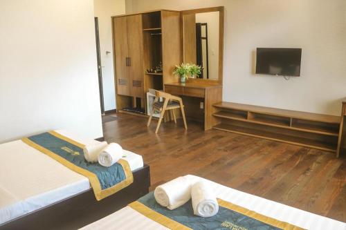 a room with two beds and a desk and a television at HON BA LAGI BEACH RESORT in La Gi