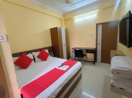 a bedroom with a bed with red pillows and a desk at Hotel K A Square in Bhopal