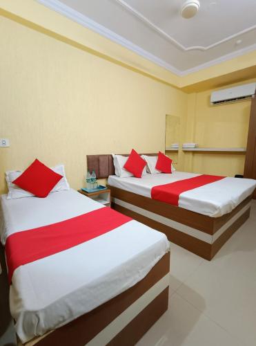 two beds in a hotel room with red pillows at Hotel K A Square in Bhopal