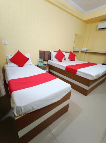 two beds in a hotel room with red pillows at Hotel K A Square in Bhopal