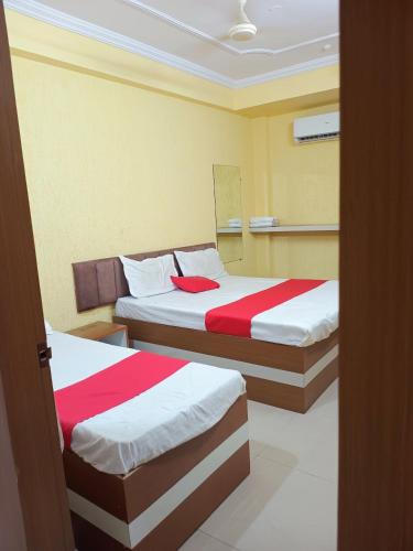 a bedroom with two beds with red and white sheets at Hotel K A Square in Bhopal