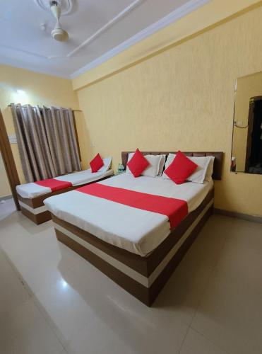 two beds in a hotel room with red pillows at Hotel K A Square in Bhopal