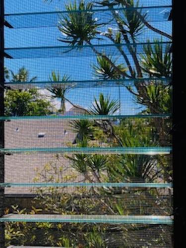 a fence with palm trees and a building behind it at Princeville Townhouse Apt - Views, Pool, Near Hanalei! in Princeville