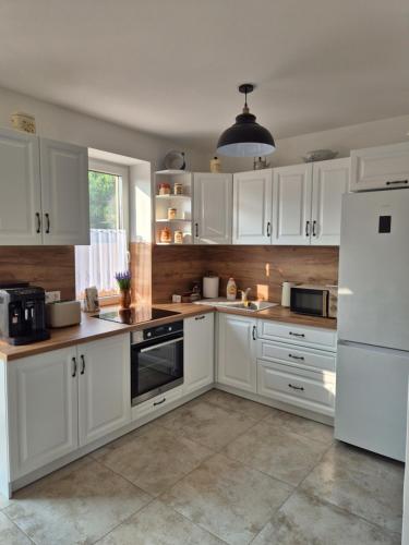 a kitchen with white cabinets and a white refrigerator at PoroszLove Vendégház in Poroszló