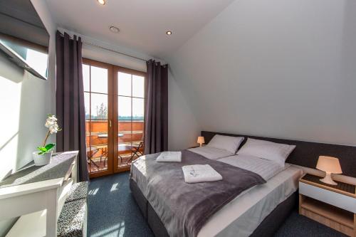 a bedroom with a bed and a large window at Apartamenty, pokoje PRZY TERMACH - 70 m Termy Szaflary, 150 m Gorący Potok in Szaflary