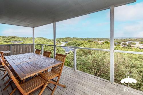 a wooden table and chairs on a deck with a view at 37 Oceanview Parade Sandy Point in Sandy Point