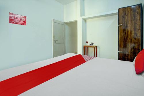 a bedroom with a white bed with a red stripe on it at Super Hotel O Pragya New in Raipur