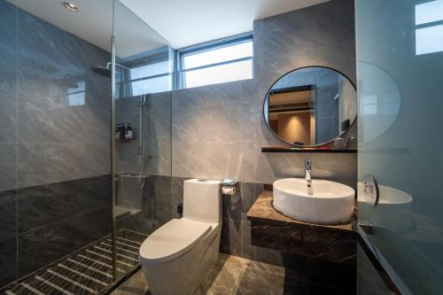 a bathroom with a toilet and a sink and a mirror at Zhuhai Jinjunyao Hotel in Zhuhai