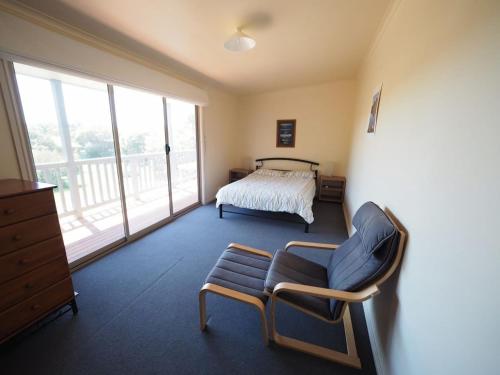 Un dormitorio con una cama y una silla y una ventana. en Sunset Deck Beach House Sandy Point, en Sandy Point