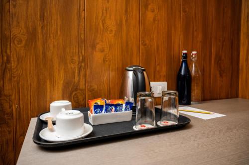 a tray with a coffee maker and glasses on a table at Hotel Asrani International in Secunderabad