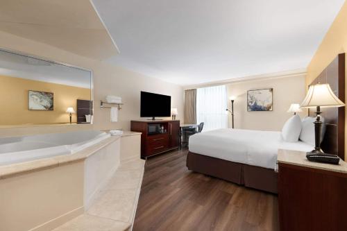 a large hotel room with a large bed and a tub at Wyndham Riverfront Hotel in Little Rock