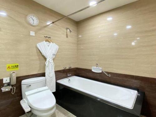 a bathroom with a tub and a toilet and a clock at Changchun Zhuozhan Days Hotel in Changchun
