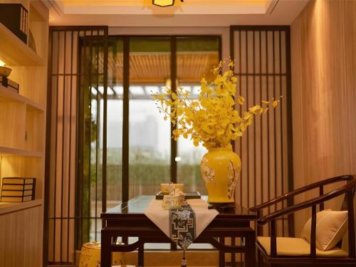 a table with a vase with yellow flowers on it at Yuan Culture Hotel Shenzhen World Shajing in Shenzhen