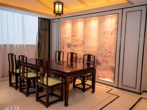 a dining room table with chairs and a painting at Yuan Culture Hotel Shenzhen World Shajing in Shenzhen