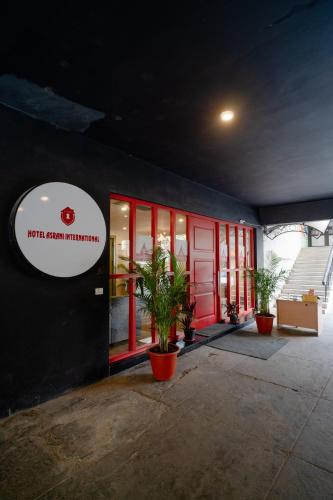 a building with a red door and potted plants outside at Hotel Asrani International in Secunderabad