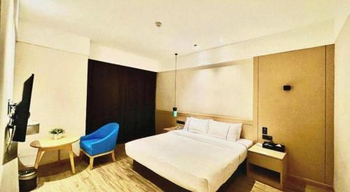a hotel room with a bed and a blue chair at City Comfort Inn Wuhan Wansongyuan Wangjiadun East Metro in Wuhan