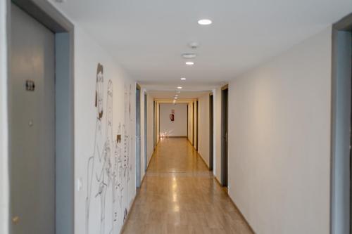 a hallway with white walls and a long hallway with wood floors at Hotel Asrani International in Secunderabad