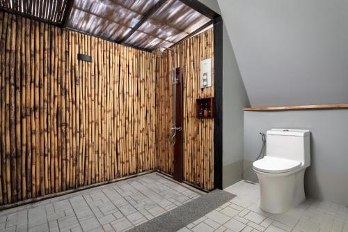 a bathroom with a toilet and a wooden wall at Summer Bay Beach Club & Cabins Sihanoukville by Preference in Sihanoukville