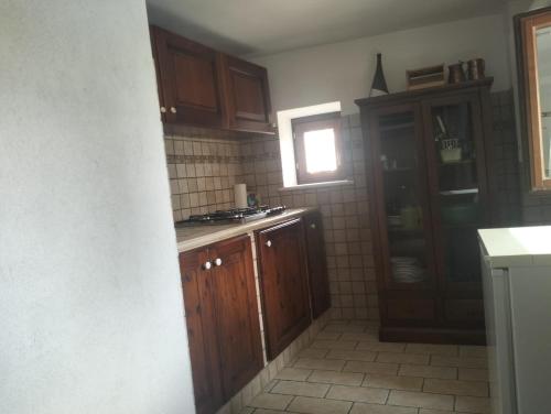 a kitchen with wooden cabinets and a window at il cortile in Calascio