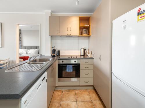 a small kitchen with a sink and a stove at Fabulous apartment in The Atrium, Mt Maunganui in Mount Maunganui