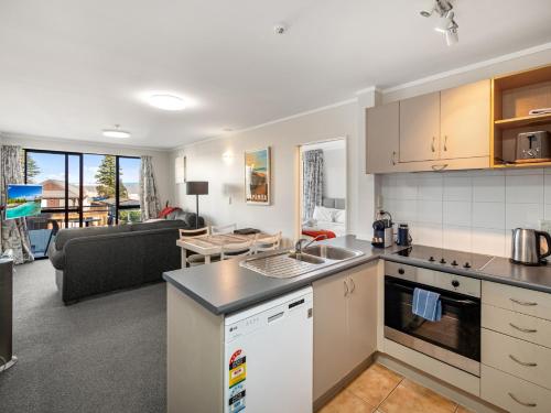 an open kitchen and living room with a couch at Fabulous apartment in The Atrium, Mt Maunganui in Mount Maunganui