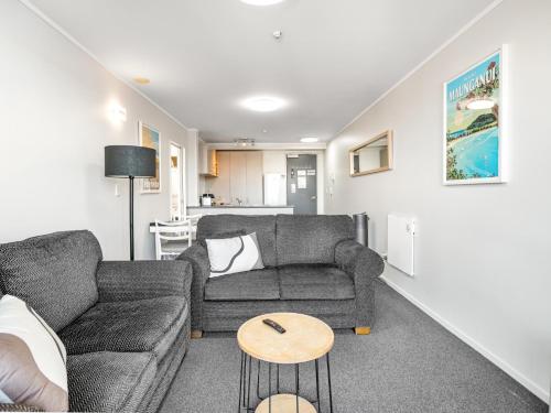 a living room with a couch and a table at Fabulous apartment in The Atrium, Mt Maunganui in Mount Maunganui