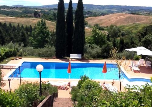 a large swimming pool with umbrellas and trees at Casale del Vacanziere in Certaldo