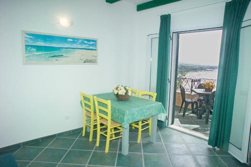 a dining room with a table and chairs and a balcony at Appartamenti Tallinucci in Lacona