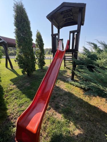a red slide in a park with a gazebo at Popasul Caprioarei in Pădureni