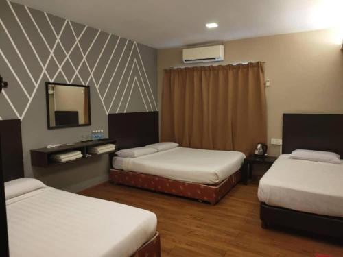 a hotel room with two beds and a mirror at Sea Lion Hotel Pulau Ketam in Bagan Teochew