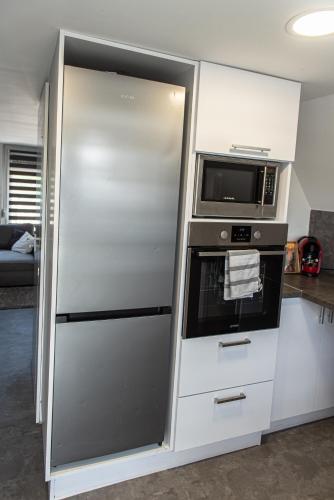 a stainless steel refrigerator in a kitchen with a microwave at PilisRelax-Stílusos Vendèghàz in Pilismarót