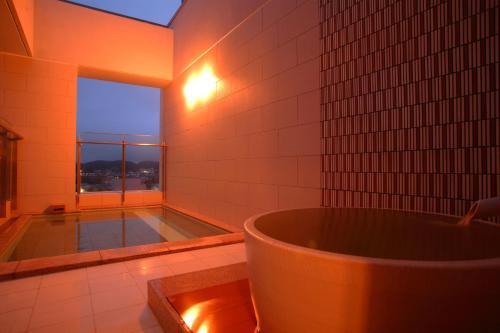 
a bathroom with a tub and a bathtub in it at Spa Hotel Alpina Hida Takayama in Takayama
