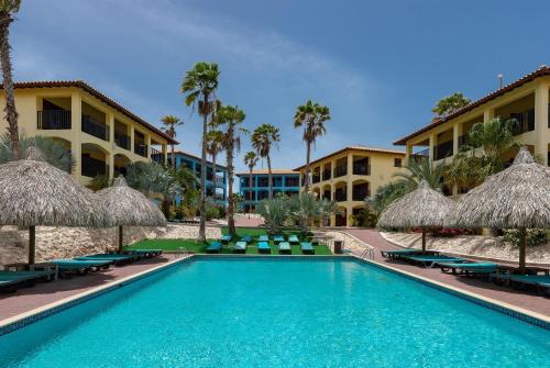 a pool with chairs and umbrellas in front of a resort at Kunuku Resort All Inclusive Curacao, Trademark by Wyndham in Willemstad