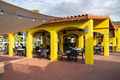 a yellow pavilion with tables and chairs on a patio at Kunuku Resort All Inclusive Curacao, Trademark by Wyndham in Willemstad