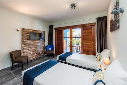 a hotel room with two beds and a balcony at Kunuku Resort All Inclusive Curacao, Trademark by Wyndham in Willemstad