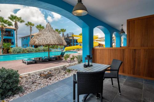 an outdoor patio with a table and chairs and a pool at Kunuku Resort All Inclusive Curacao, Trademark by Wyndham in Willemstad