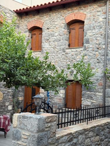 a stone building with brown windows and a fence at Villa GIANNAKOS MINOAN HERSONISSOS in Kastéllion