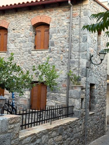 a stone building with brown windows and a fence at Villa GIANNAKOS MINOAN HERSONISSOS in Kastéllion