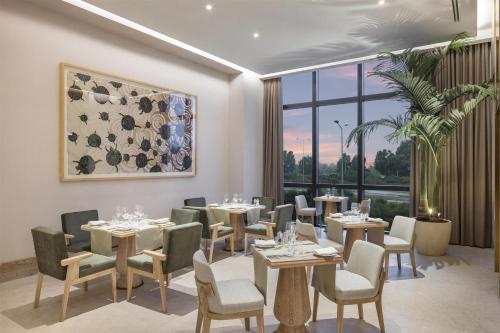 a restaurant with tables and chairs and a large window at Hyatt Regency Izmir IstinyePark in Izmir