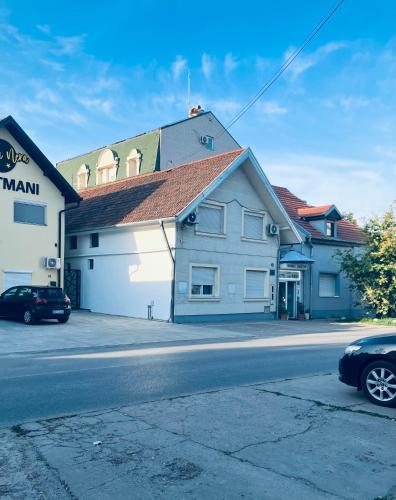 a building with a car parked next to a street at Lovely Garden 100m2 apartment in Novi Sad